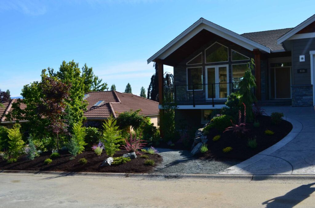 DSC_1054-scaled Landscaping example: This home is on a hill, so the landscaping project had to reflect the geography of the area. A pathway curves down towards the side of the home, bordered by flower gardens.