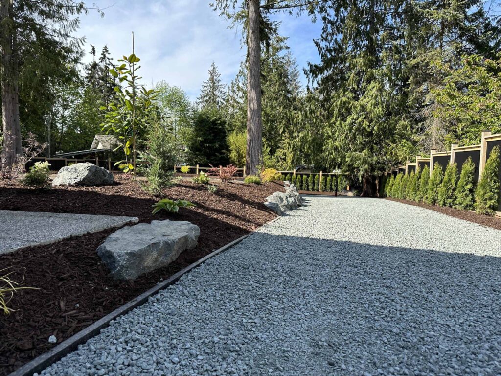 IMG_0557-scaled Landscaping example: An overview of a gravel driveway, a hedge lined fenceline, small stone retaining wall, and carefully selected foliage.